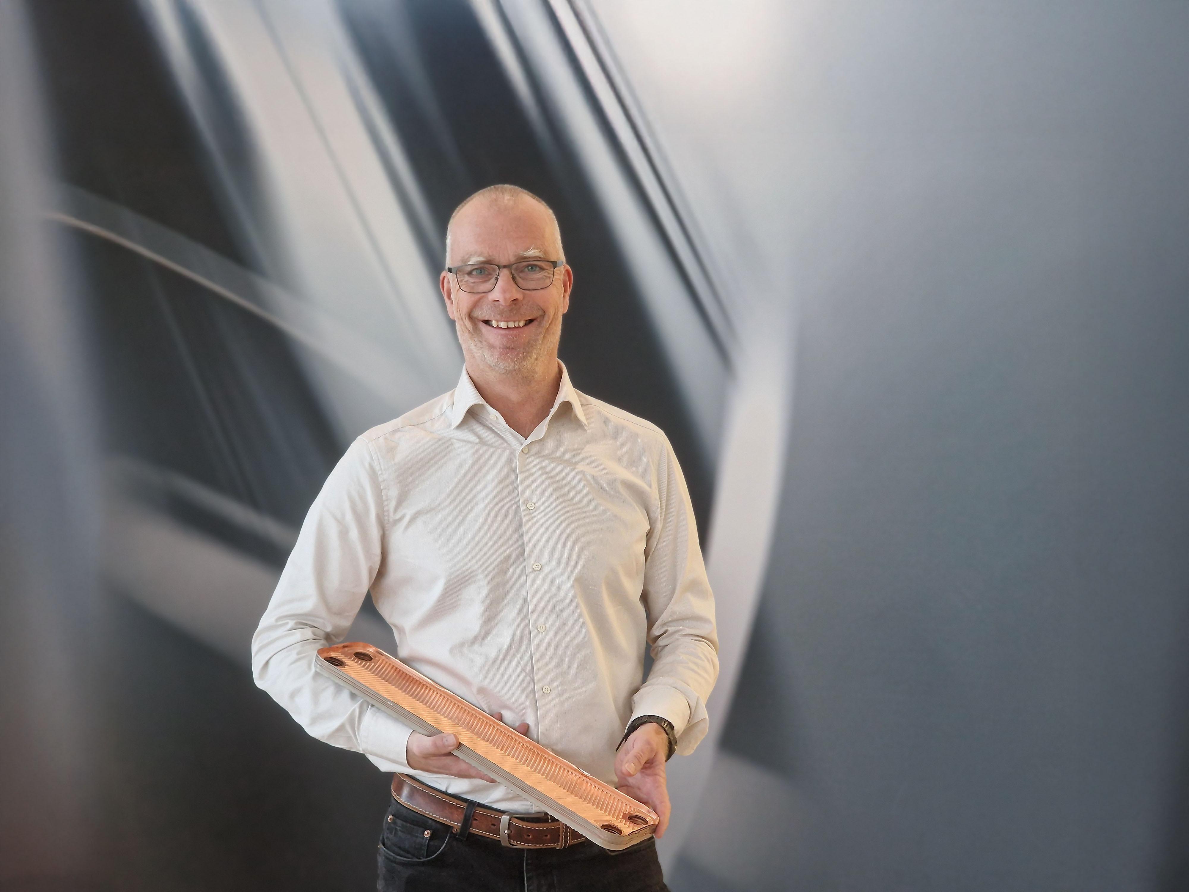 生产线解决方案业务经理 Lennart Johansson 展示了 AP&T 伺服驱动生产线制造的板式换热器片样品，该生产线专为满足日益增长的热交换器片需求而设计，兼具高产能和低能耗的特点